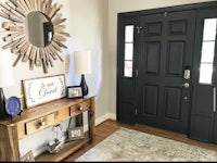 a black front door with a wooden table and a mirror
