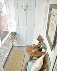 a small porch with a wooden table and chairs